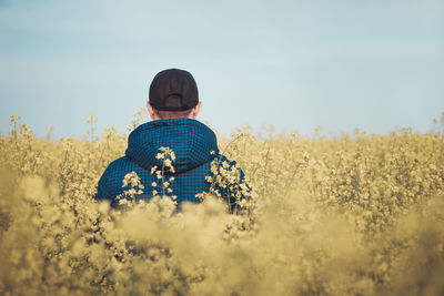 Rear view of man in field against sky