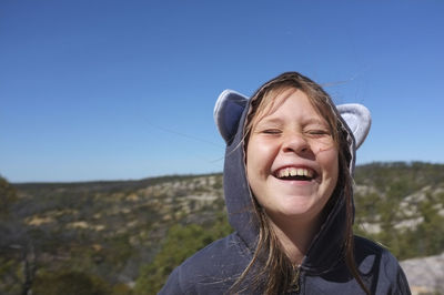 Portrait of smiling young girl against clear sky