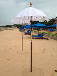 Deck chairs on beach against sky