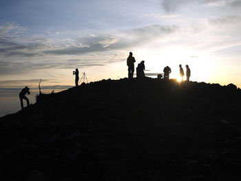 Silhouette people standing against sky during sunset