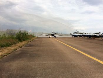 Airplanes at airport runway against sky