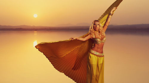 Portrait of mid adult woman wearing costume by lake during sunset