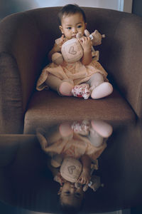 Cute baby girl sitting on sofa at home