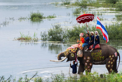 People riding elephant in lake
