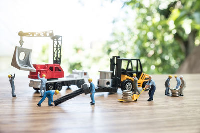 Close-up of figurines with toy crane and forklift with equipment on table