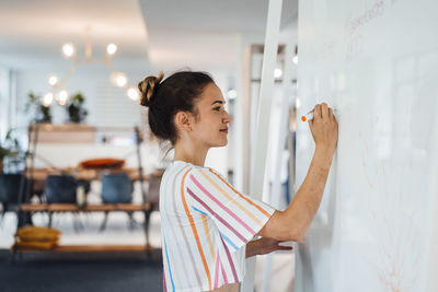 Businesswoman writing on whiteboard in office