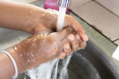 Cropped image of hand touching water in bathroom at home