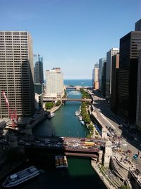 Modern cityscape by river against sky