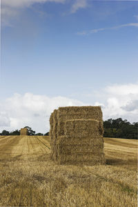 Hay bales on field against sky