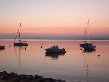 Boats in sea at sunset