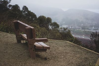 Empty bench on field against sky