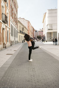 Woman walking on footpath amidst buildings in city