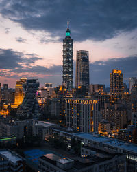 Illuminated buildings in city against sky during sunset