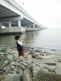 Rear view of man standing in sea against sky