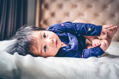 Portrait of young woman lying on bed at home