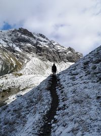 Full length of person standing on trail against sowcapped mountain