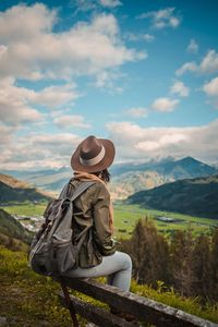 Rear view of woman standing on mountain against sky