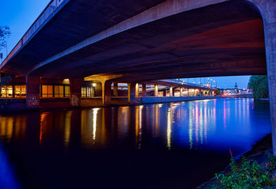 Illuminated bridge over river against sky at night