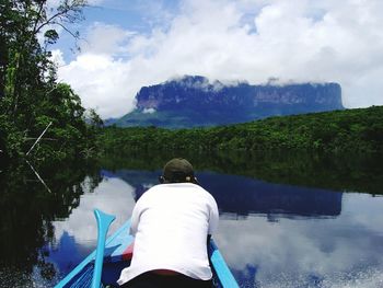 Rear view of man on lake against sky