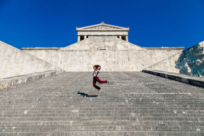 Full length of man cycling on staircase against sky