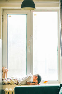 Side view of boy sleeping in glass window