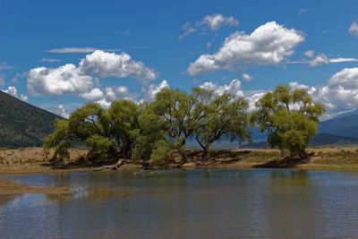 Calm countryside lake against cloudy sky