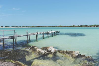 Pier over sea against clear blue sky
