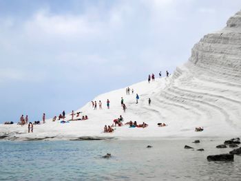 People enjoying at beach against sky