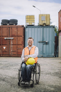 Portrait of smiling construction worker sitting in wheelchair at site