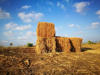 Hay bales on field against sky