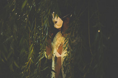 Young woman wearing mask while standing amidst leaves