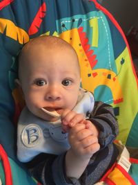 Portrait of cute baby boy carrying spoon in mouth