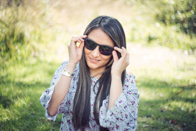 Portrait of smiling young woman wearing sunglasses standing outdoors