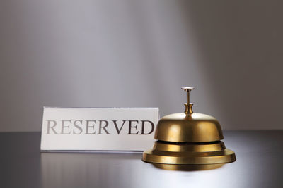 Close-up of reserved place card with service bell on table
