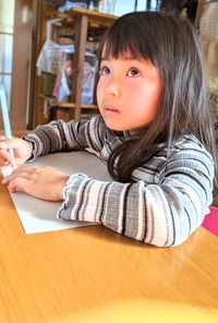 Portrait of girl sitting on table