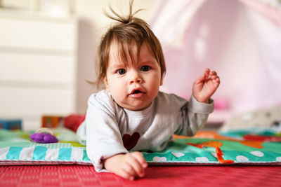 Portrait of cute baby girl lying at home