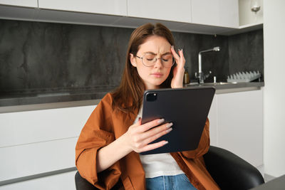 Portrait of young woman using laptop while sitting at home