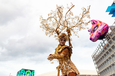 Low angle view of statue by building against sky