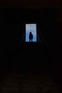 Rear view of silhouette man walking on staircase