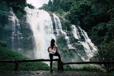 Man sitting by waterfall in forest