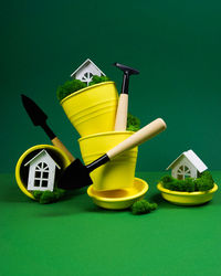 Creative photo on a green background with yellow flower pots and garden tools