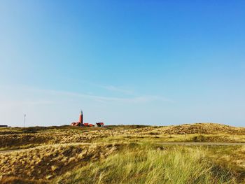 Scenic view of grassy field against clear blue sky 