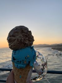 Midsection of woman at beach against sky during sunset