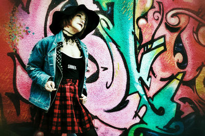 Full length of woman standing against graffiti wall