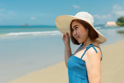 Young woman wearing hat while standing on beach