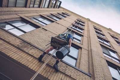 Low angle view of window washer on building