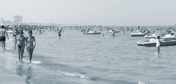 Group of people on beach against clear sky