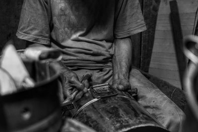 Midsection of man working on metal