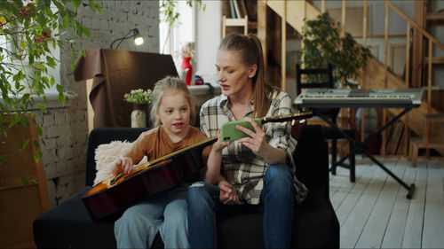 Mother teaching guitar to daughter at home