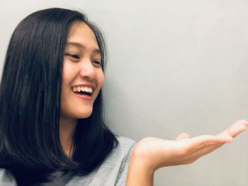 Portrait of smiling young woman against wall